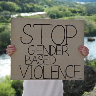 Woman holding sign with text Stop Gender Based Violence outdoors