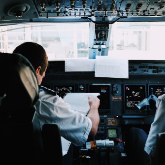 Two pilots sitting in a plane going through a checklist