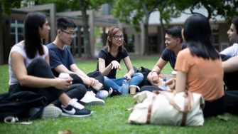 Group of students sitting on grass on campus
