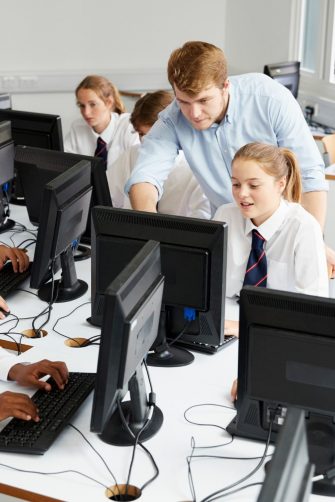 Teenage Students Wearing Uniform Studying In IT Class