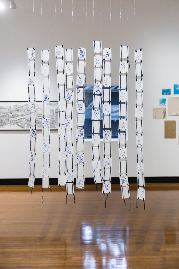 Fatima Naqvi, ‘Blind Faith’ (2025). Blue ink stamped with prayer bead on 99 A7 panels joined together using eyelet rings and blue thread; 94.5cm x 81.4cm. Photograph: Anna Kucera.