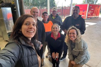 seven people are smiling for the camera, with one person holding it in a selfie pose