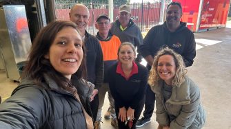 seven people are smiling for the camera, with one person holding it in a selfie pose