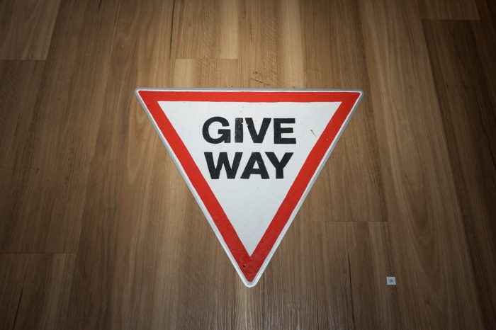 Allyson Brown, ‘Boundary St’ 2026. Wall mounted sign: Spray paint on metal, 50cm x 183cm. Triangle ‘give way’ sign: Acrylic and ochre on metal, 80cm x 80cm (80 cm each side). Free standing ‘authorised persons only’ sign: Acrylic and ochre on metal, 104cm x 93cm x 70cm.