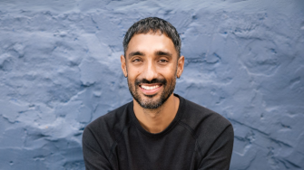 Researcher Andrew Brooks smiles at the camera for a portrait. He has dark hair and a beard.