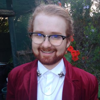 A photo of Axel-Nathaniel Rose. He is a white man in his 20s, with red hair and glasses.