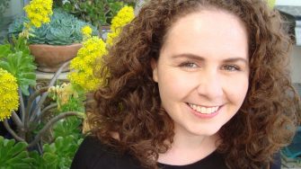 Researcher Kate Brady smiles at the camera in front of thriving succulent garden.
