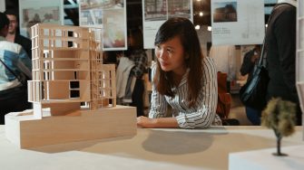 Student looking at a wooden model of a building