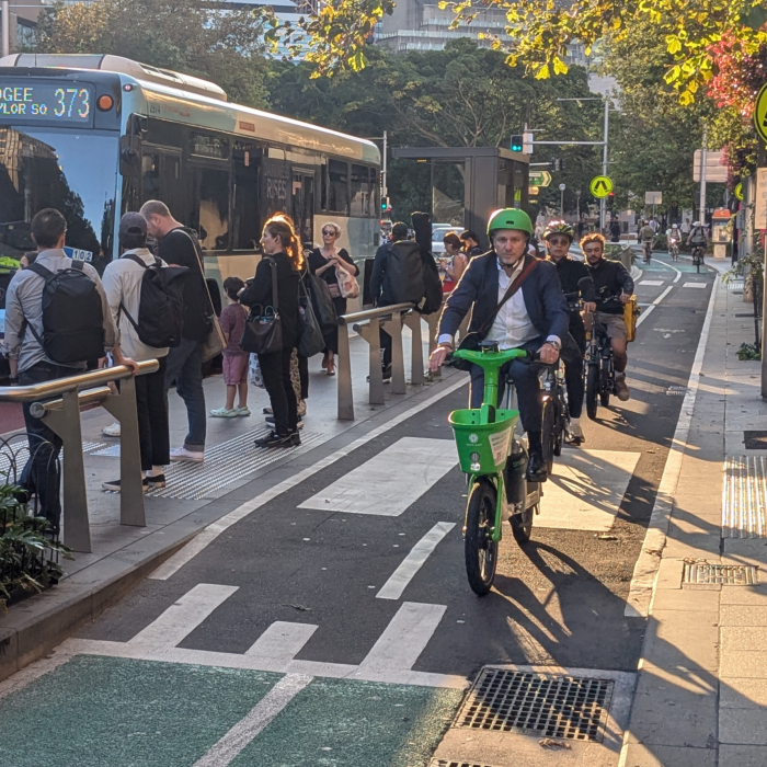 people cycling in cycle path along bus