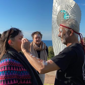 Indigenous man spreading ochre on woman's face