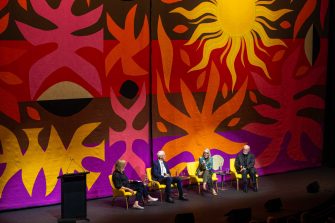 Four panel members on stage in front of colourful backdrop
