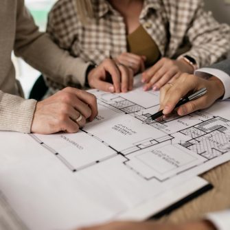 Mid shot of three people's hands on a house blueprint