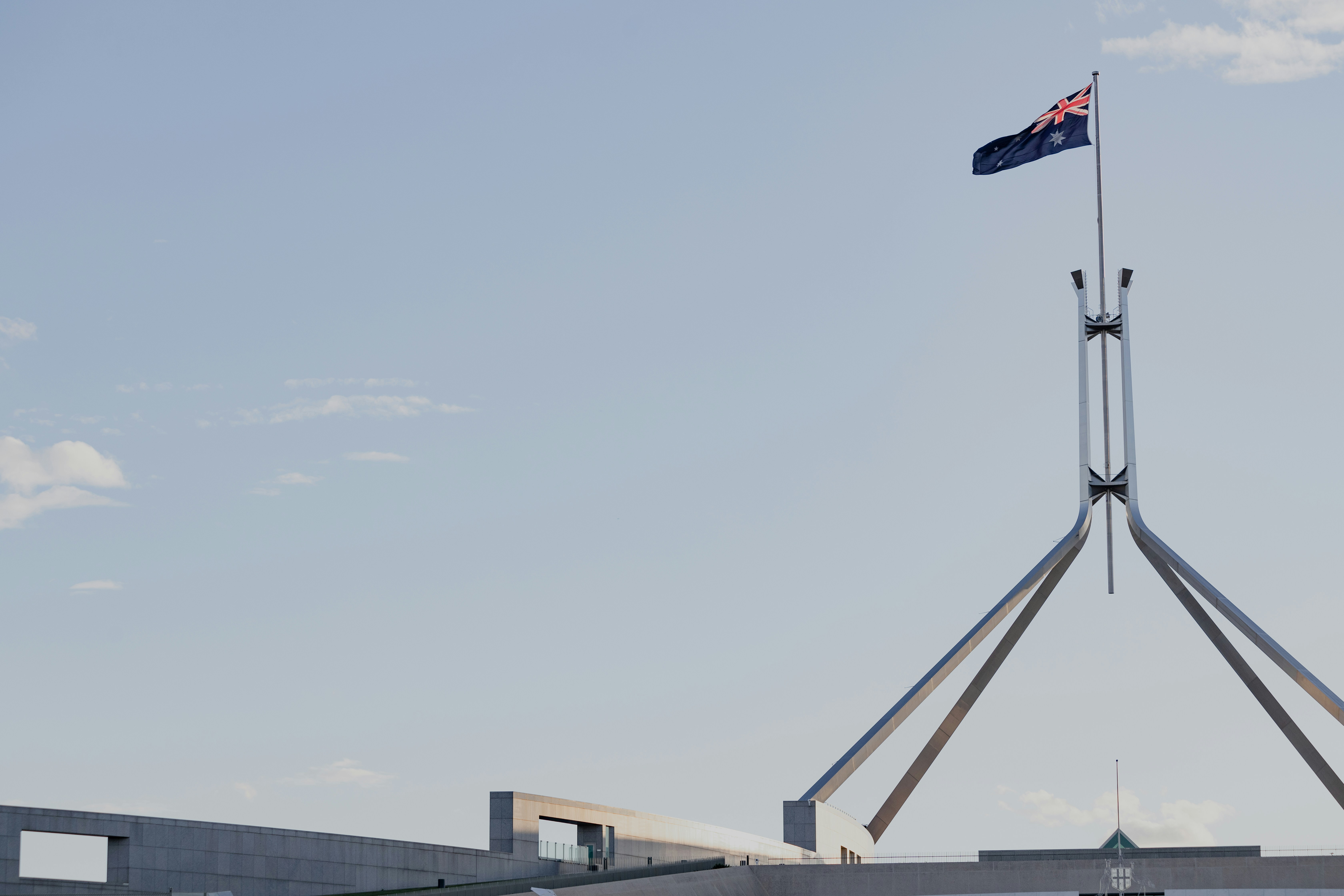 An Australian flag blows in the wind against a blue sky