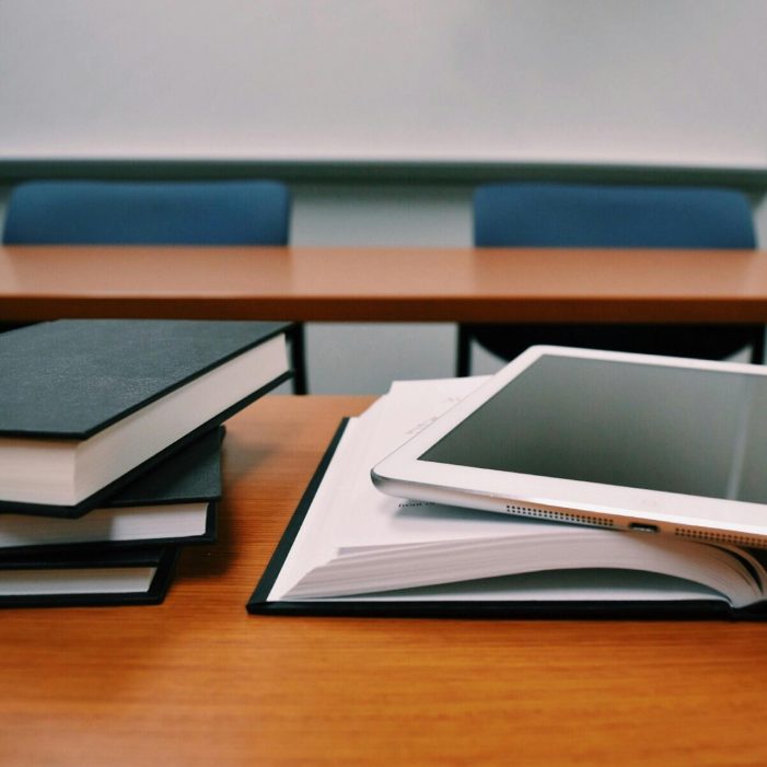 An iPad and stack of books on an empty desk
