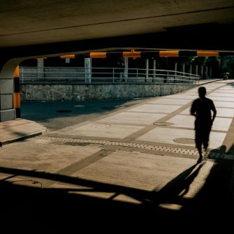 A silhouette of a person runs through an empty underpass