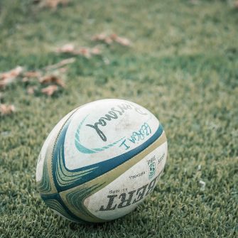 A lone rugby ball against green grass