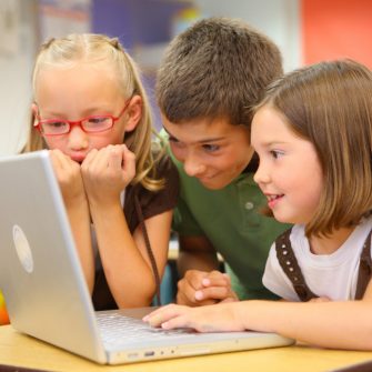 Elementary school students look at laptop computer stock photo