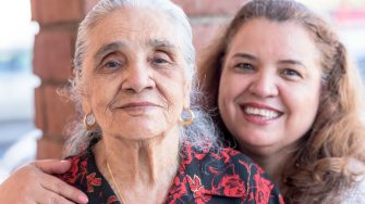 Smiling hispanic mother and daughter posing together