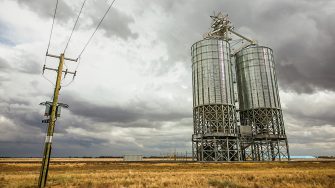 Power lines and infrastructure in the outback at Dubbo, NSW, the grass is brown and the sky filled with grey clouds, just before rain sets in.