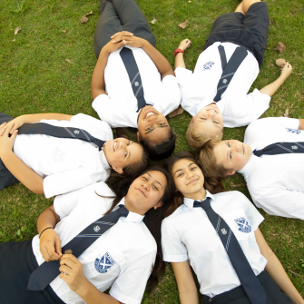 a group of children laying on the grass making a shape of star