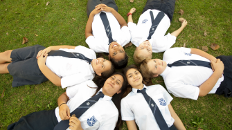 a group of children laying on the grass making a shape of star