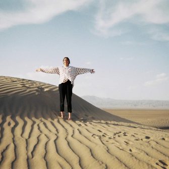 Maya Skidmore standing on desert sand dunes
