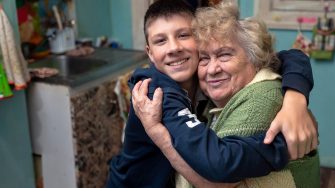 Happy, smiling grandson hugs his grandmother
