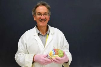 Emeritus Professor Ken Ashwell holding a brain