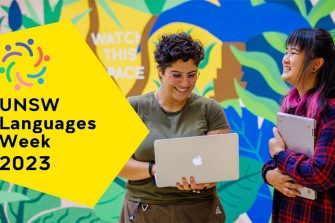students in front of mural with laptop