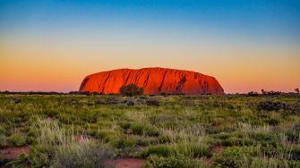 Uluru , Australia - August 21, 2016: Changing colour at sunset of Uluru, the famous gigantic monolith rock in the Australian desert. Image taken from the approved public viewing and photography area.