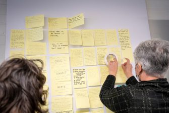 Person placing sticky note on display board