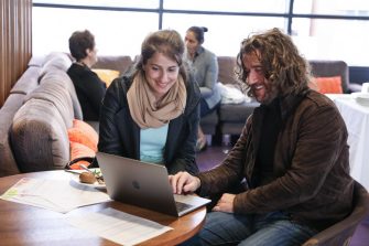 Two participants collaborating over a laptop in a lounge area at the STEP UP 2019 conference.