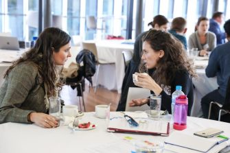 Two attendees in conversation over coffee at a conference table during STEP UP 2019.