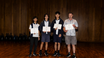 Three students holding the certificate along with their teacher in Alexandria park School