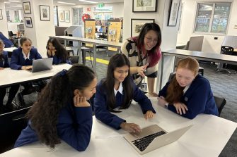UNSW facilitator helping Caroline Chisholm College students work on a laptop in the school library