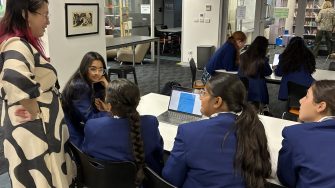 Caroline Chisholm College students gathered around a laptop with a UNSW facilitator during the Step Up school visit