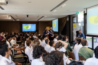Students in white and navy uniforms holding UNSW Step Up certificates with a UNSW staff member and a UNSW Sydney tote bag at Arthur Phillip High School in 2022