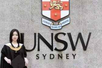 Jinting Ke in graduating gown in front of UNSW sign