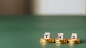 The letters T-A-X sitting atop coins