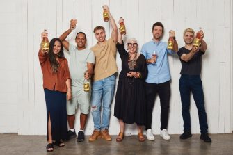 Smiling people holding bottles of OzHarvest Ventures wine