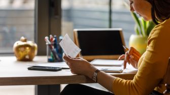 Copy space shot of diligent young woman sitting at home office desk, using a calculator and sorting out various finances and bills.