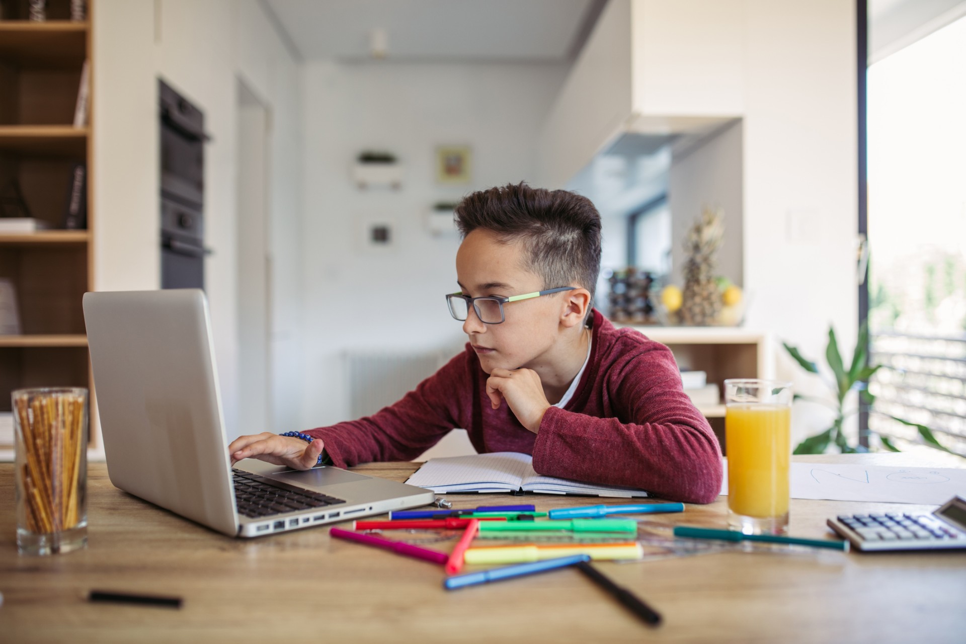 One man, young boy is tired of doing homework, sitting at the table, using laptop.