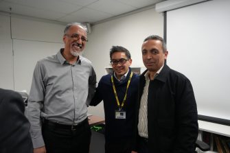 Three men are standing together during the panel event.