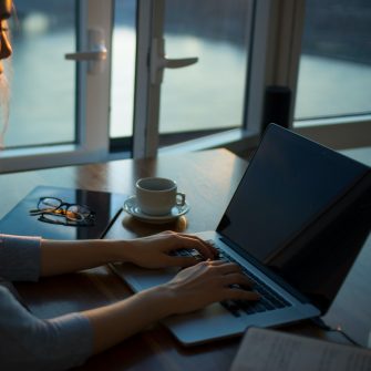 Person using laptop with coffee and glasses on desk