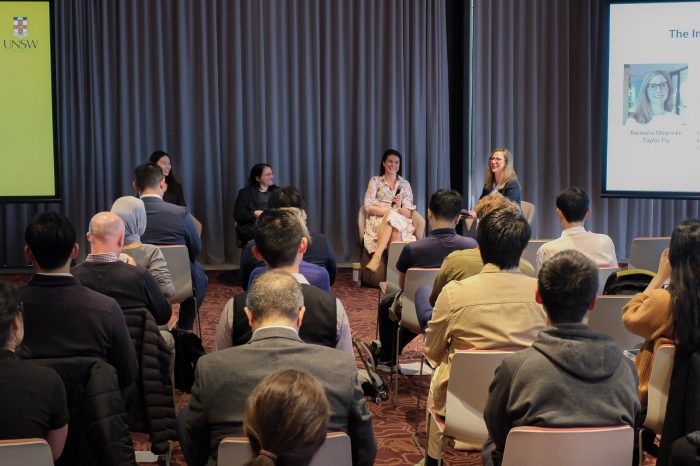 A panel sits on stage in front of workshop attendees.