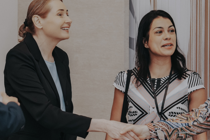 Two ladies gretting a guest at a UNOVA event