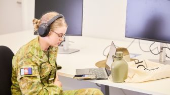 A woman wearing headphones at her computer