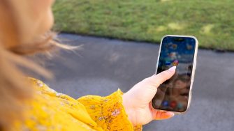 PhD student Karoline Thomsen holding phone showcasing social media icons