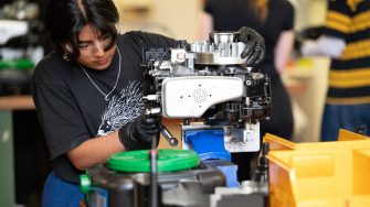 A young woman working on assembling a motor.
