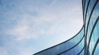 Perspective of high rise building and dark steel window system with clouds reflected on the glass.Business concept of future architecture,lookup to the angle of the building corner. 3d rendering